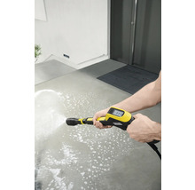 Een persoon reinigt een betonnen oppervlak met een gele hogedrukreiniger.