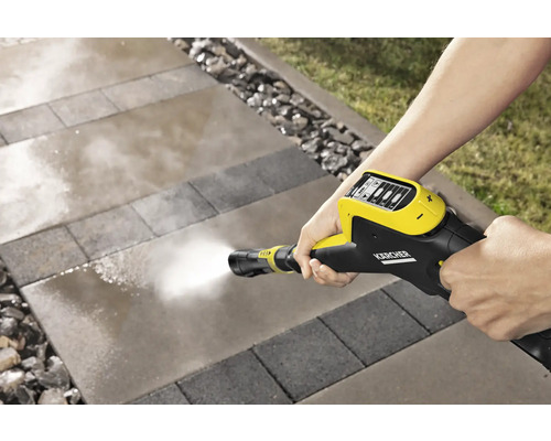 Een persoon reinigt bestrating met een Kärcher hogedrukreiniger.