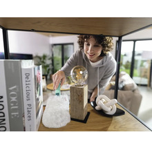 Vrouw stofzuigt gloeilamp op een plank