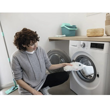 Vrouw legt een dweilhoes in een wasmachine