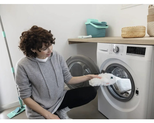 Vrouw legt een dweilhoes in een wasmachine