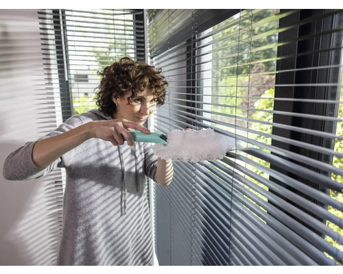 Vrouw reinigt jaloezieën met plumeau
