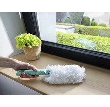 Persoon houdt plumeau met handvat vast voor reiniging op vensterbank