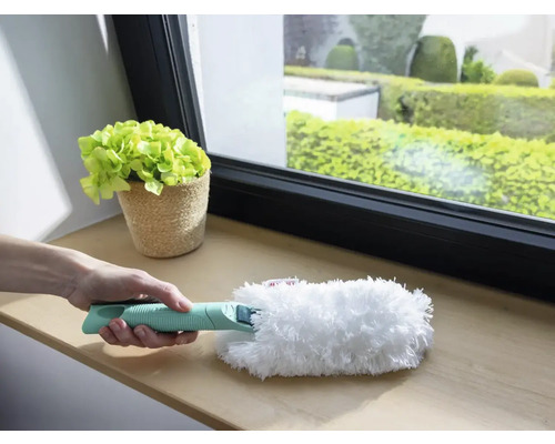 Persoon houdt plumeau met handvat vast voor reiniging op vensterbank