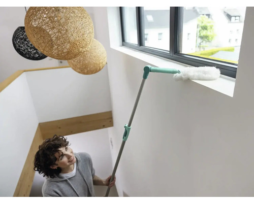 Vrouw reinigt vensterbank met een plumeau.