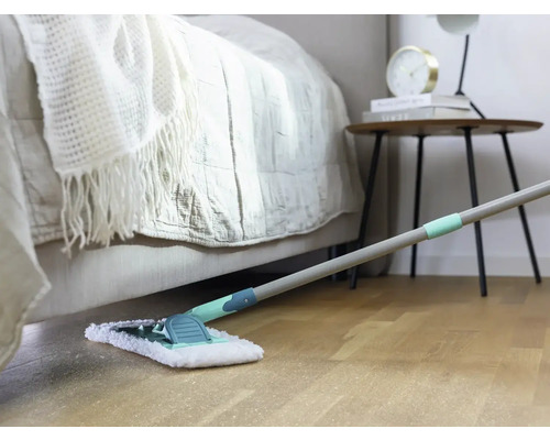 Scene van een kamer met bed, nachtkastje en dweil op een houten vloer.