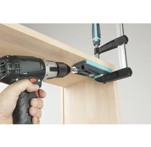 Accuboormachine die door een boorgeleider in een houten plank boort