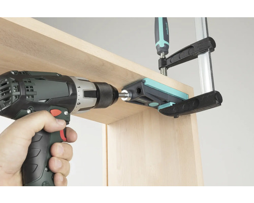 Accuboormachine die door een boorgeleider in een houten plank boort