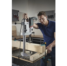Man boort met een tafelboormachine een gat in een houten plank