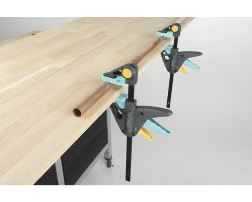 Werkbank met twee Wolfcraft éénhandklemmen en een koperen buis.