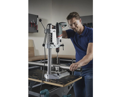 Man boort met een tafelboormachine een buis op een werkbank