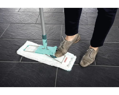 Vloermop in gebruik op donkere tegels, bediend door een persoon met schoenen.