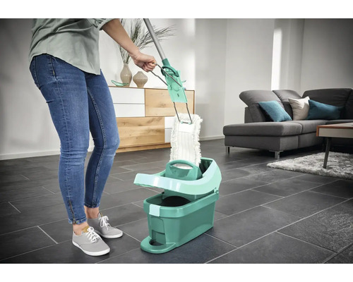 Vrouw gebruikt dweil met emmer in de woonkamer voor vloerreiniging