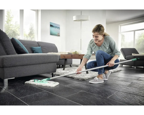 Vrouw dweilt vloer in woonkamer met mop