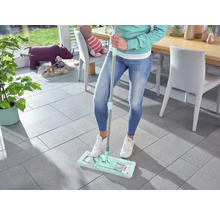 Vrouw dweilt tegelvloer met een mop