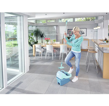 Vrouw gebruikt een dweilset in een lichte kamer met een tegelvloer.