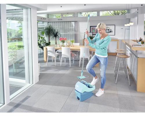 Vrouw gebruikt een dweilset in een lichte kamer met een tegelvloer.