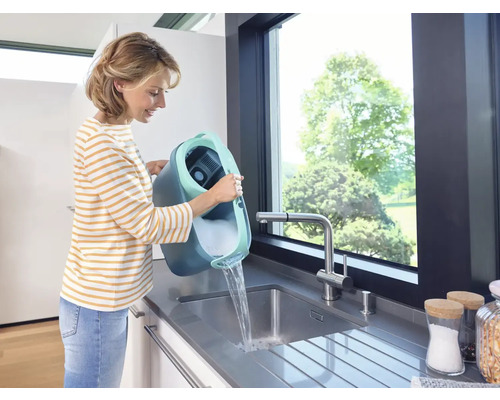 Vrouw giet emmer met reinigingsmiddel in een gootsteen