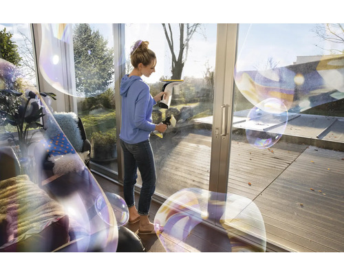 Vrouw reinigt ramen met een raamzuiger voor streeploze reinheid.