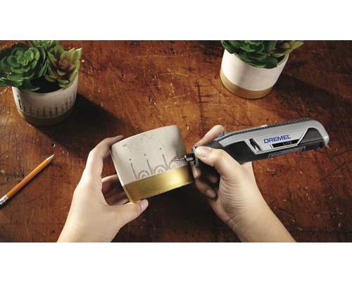 Scène van het graveren van een bloempot met een Dremel Lite gereedschap op een houten oppervlak.