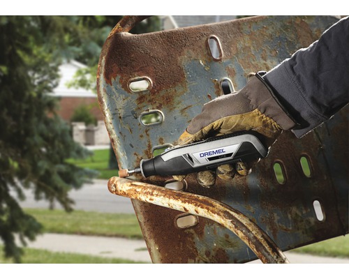 Een persoon gebruikt een Dremel gereedschap om roest van een metalen stoel te verwijderen.