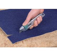 Een hand snijdt met een tapijtmes een tapijt.