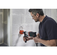 Man boort gat met een gatenzaag in de muur