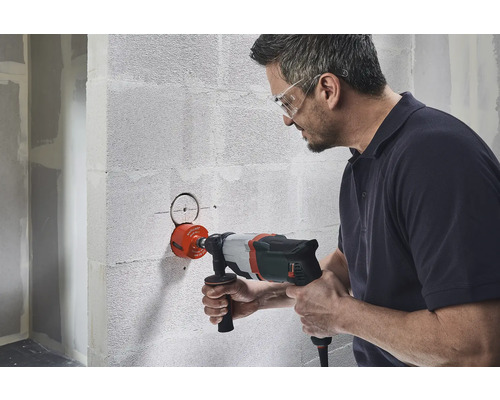 Man boort gat met een gatenzaag in de muur