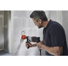 Man boort een gat in een muur met een gatzaag.