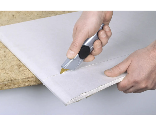 Persoon snijdt gipsplaat met een stanleymes