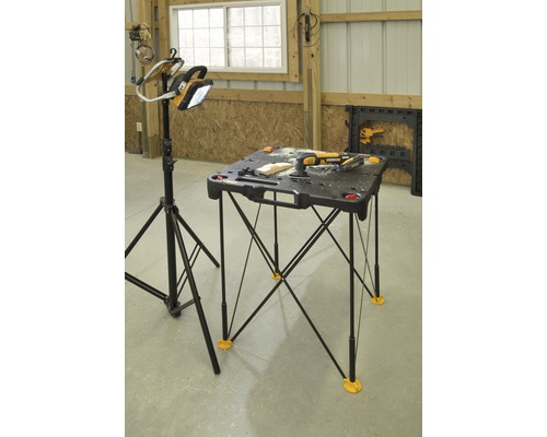Werkplaatsopstelling met een draagbare werkbank en een werklamp op statief.