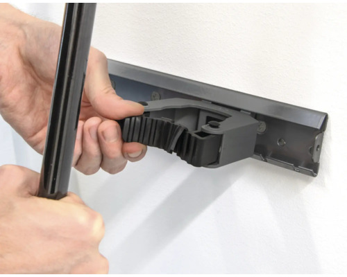 Persoon bevestigt een gereedschap aan een gereedschapshouder aan de wand.