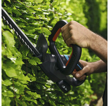 Persoon gebruikt een heggenschaar om een haag te knippen