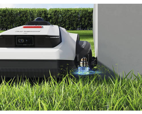 Robotmaaier op gazon in de buurt van een muur