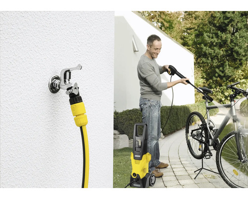 Een man maakt een fiets schoon met een Kärcher hogedrukreiniger. Ook is een waterkraan met slangaansluiting te zien.
