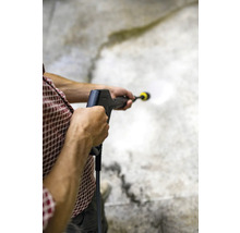 Een persoon gebruikt een hogedrukreiniger om een oppervlak schoon te maken.