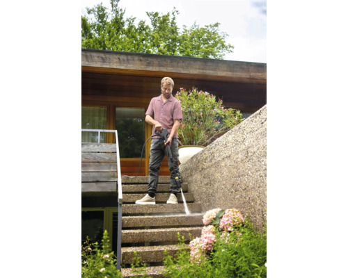 Man reinigt buitentrap met hogedrukreiniger.