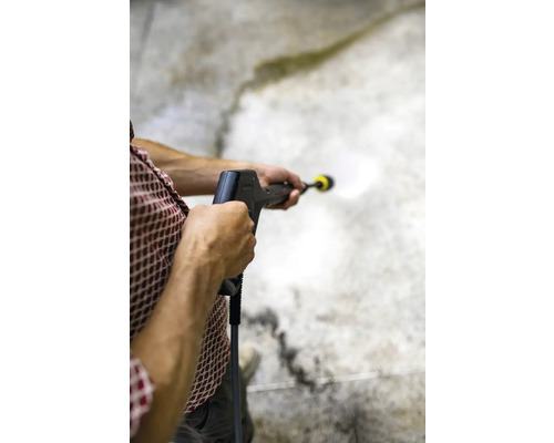 Een persoon reinigt een betonnen oppervlak met een hogedrukreiniger.