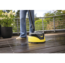 Persoon reinigt houten terras met een oppervlaktereiniger.