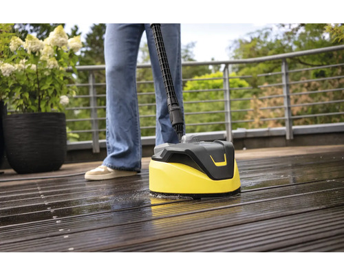 Persoon reinigt houten terras met een oppervlaktereiniger.