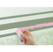 Een persoon verwijdert tape van een muur met geschilderde strepen.