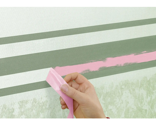 Een persoon verwijdert tape van een muur met geschilderde strepen.