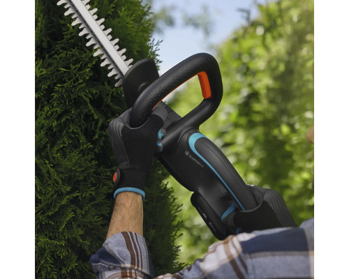 Persoon snoeit heg met Gardena accu heggenschaar