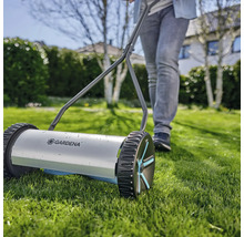 Handgrasmaaier met een persoon in de tuin.