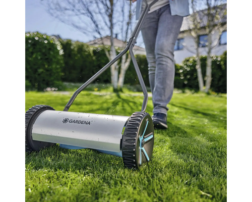 Handgrasmaaier met een persoon in de tuin.