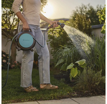 Vrouw besproeit tuin met Gardena slangbox