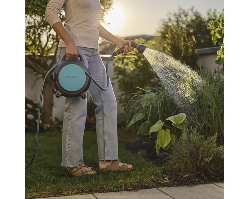 Vrouw besproeit tuin met Gardena slangbox