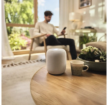 Inrichting van een woonkamer met een slimme speaker op een tafel.