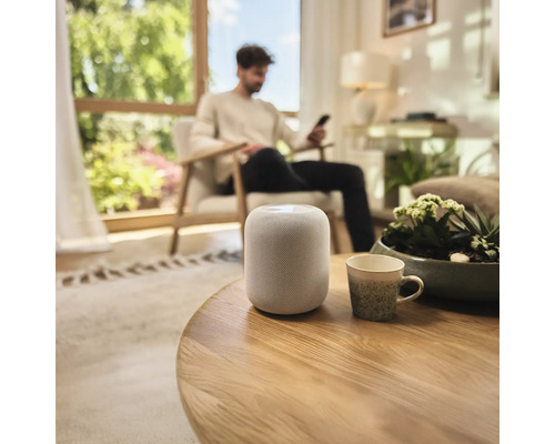 Inrichting van een woonkamer met een slimme speaker op een tafel.