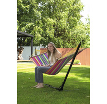 Vrouw zit in een gestreepte hangmat met frame in de tuin.